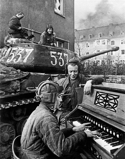 Танковый экипаж лейтенанта Б.И. Дегтярёва на отдыхе. Башенный стрелок Б.В. Калякин играет экипажу классику. Рядом стоит механик-водитель А.И. Козейкин. 1-й Украинский фронт, 87-й гвардейский тяжёлый танковый полк, г. Бреслау. 