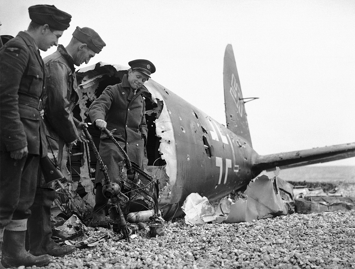 Английские солдаты рассматривают искореженные 7.92 мм бортовые пулеметы МG15 сбитого немецкого бомбардировщика Не-111, июль 1940 г.