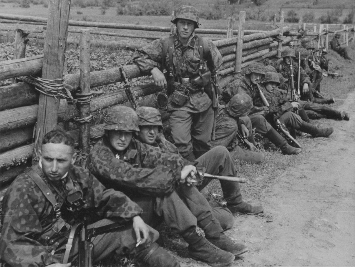  Солдаты на отдыхе у забора в советской деревне. Солдат на переднем плане слева вооружен МР-38. 1941 год.