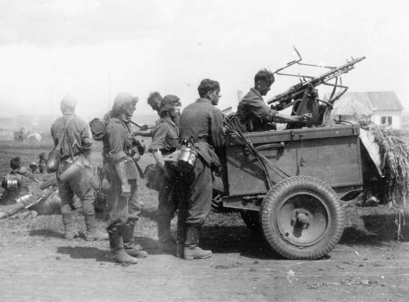 Немецкие солдаты у 7,92 мм зенитной установки Zwillingssockel-36 в населенном пункте, во время привала в ходе марша. 