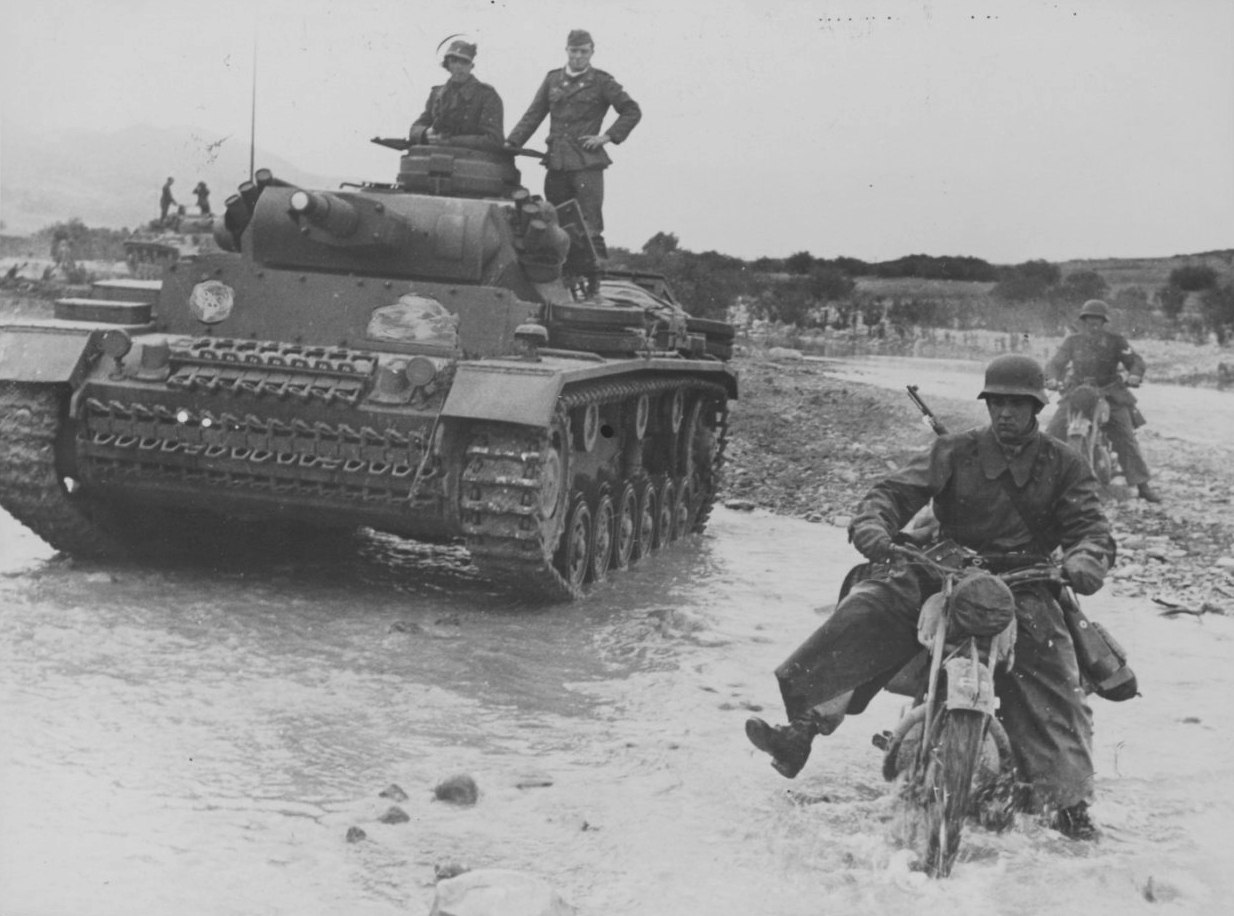 Мотоциклист Африканского корпуса вермахта и танк Pz.Kpfw. III форсируют реку Оуед Маароуф в Тунисе. 1943 г.