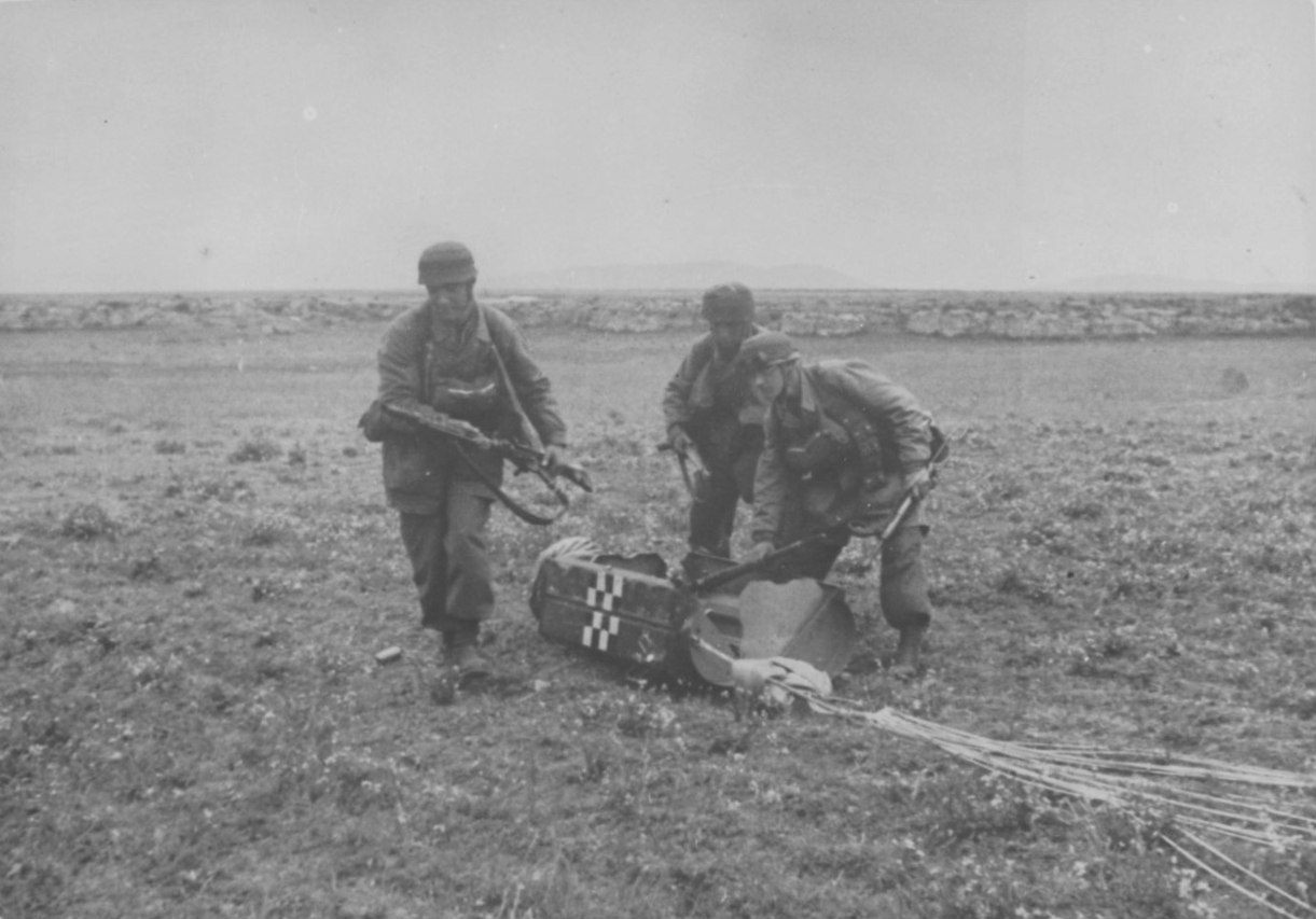 Трое парашютистов вынимают оружие из контейнера после высадки на Крите. 1941 г.